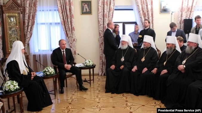 (Довоєнна фотографія. Київ, Києво-Печерська лавра, 27 липня 2013 року. Московський патріарх Кирило (ліворуч), президент Росії Володимир Путін (другий зліва), а напроти учасники синоду УПЦ (Московського патріархату), серед яких митрополит Онуфрій (другий справа)