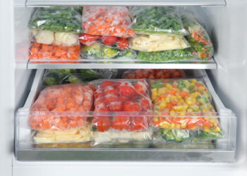 Plastic bags with different frozen vegetables in refrigerator