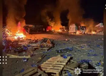 Місце атаки на Бучанщині вночі з палаючими будівлями, розбитими транспортними засобами та обломками на землі