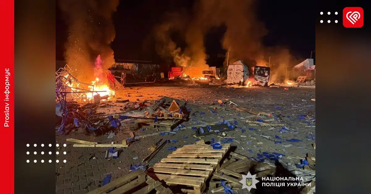 Місце атаки на Бучанщині вночі з палаючими будівлями, розбитими транспортними засобами та обломками на землі