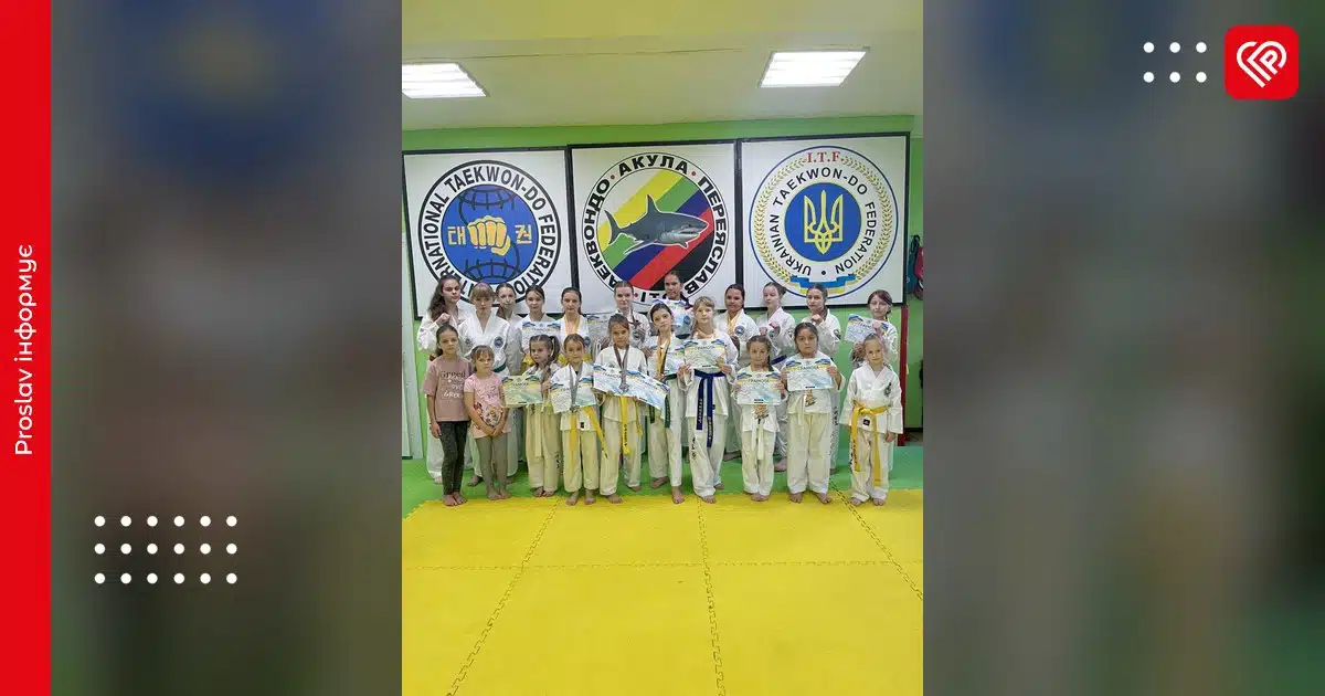 Юні спортсмени в білих кімоно та жовтих поясах позують на жовтому татамі перед логотипами федерацій таеквон-до