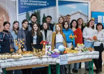 Студенти та викладачі Університету Григорія Сковороди позують біля столу з продаватими домашніми стравами на благодійному