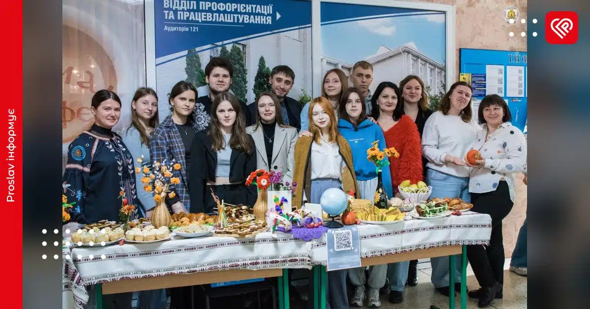 Студенти та викладачі Університету Григорія Сковороди позують біля столу з продаватими домашніми стравами на благодійному