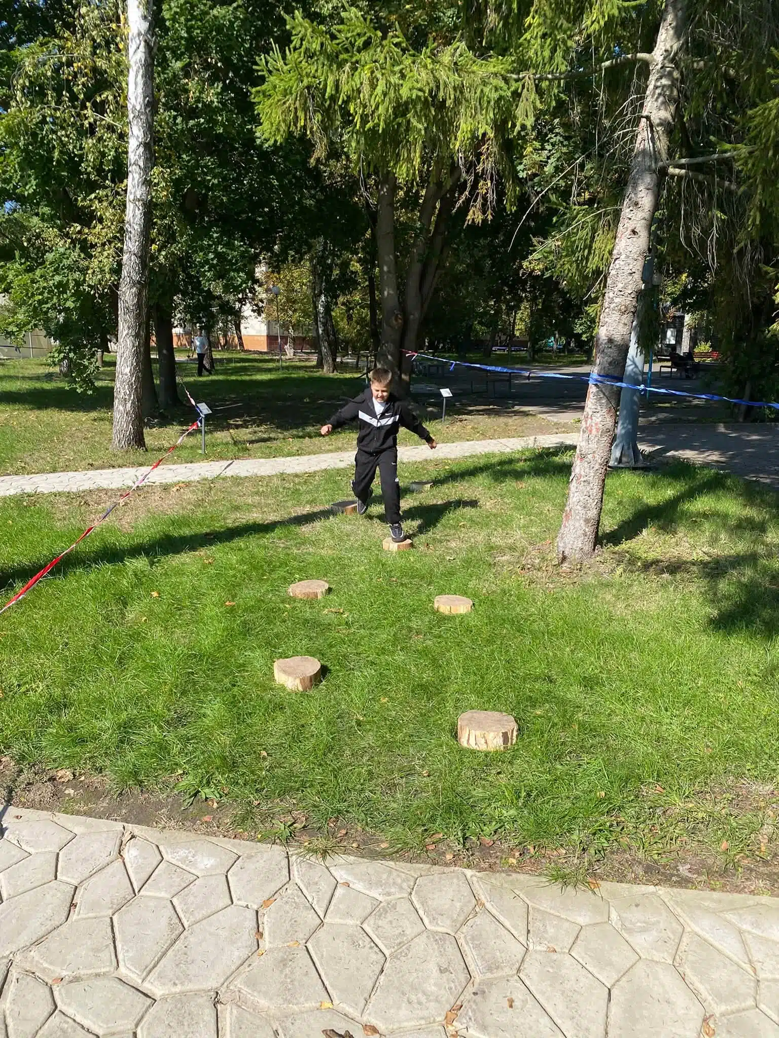 Учасник долає перешкоди смуги препон між деревами на траві парку